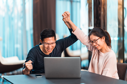 young-asian-married-couple-hold-hands-celebrating-together-watching-laptop-computer.jpg