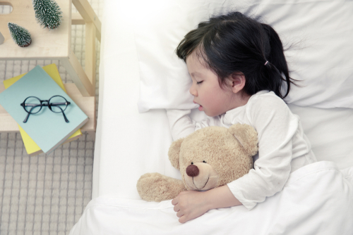 boy sleeps on side with teddy bear