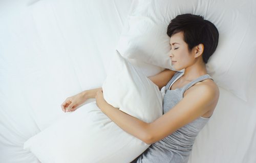 woman sleeps on side hugging pillow