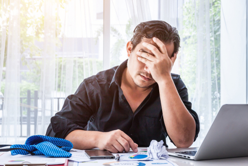 man covering eyes stressed