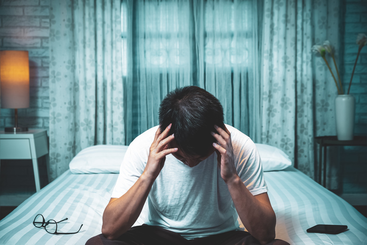 man-holding-head-in-bed-aia-malaysia
