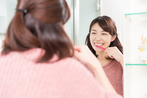 woman-brushing-teeth-looking at-mirror-aia-malaysia