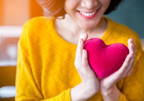 woman-hands-in-yellow-sweater-holding-pink-heart-aia-malaysia