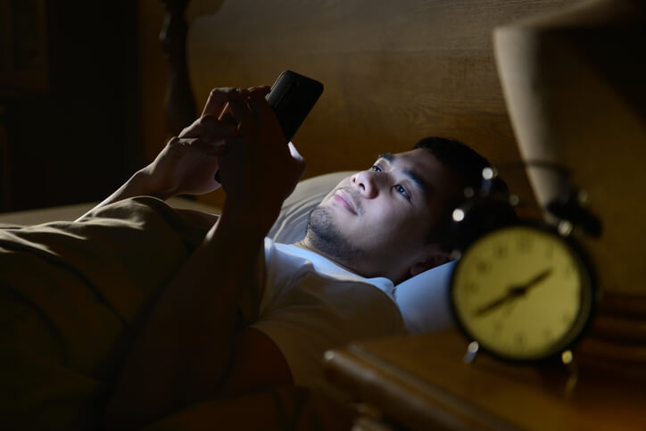 Man using phone in bed
